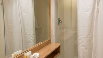 Une salle de bain avec une douche à parois de verre, un meuble-lavabo en bois avec un miroir et des toilettes blanches.