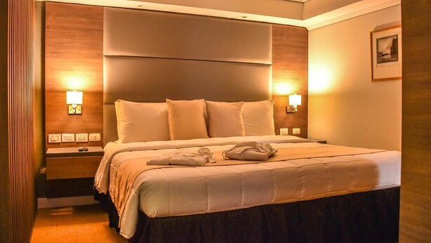 A hotel room with a large bed, bedside lamps, a nightstand, and a framed picture on the wall. - Hotel Tibisay Maracaibo (Maracaibo)