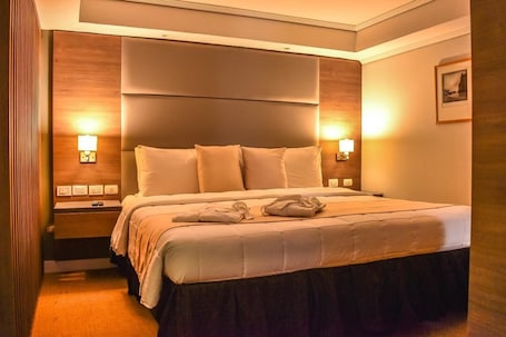 A hotel room with a large bed, bedside lamps, a nightstand, and a framed picture on the wall.