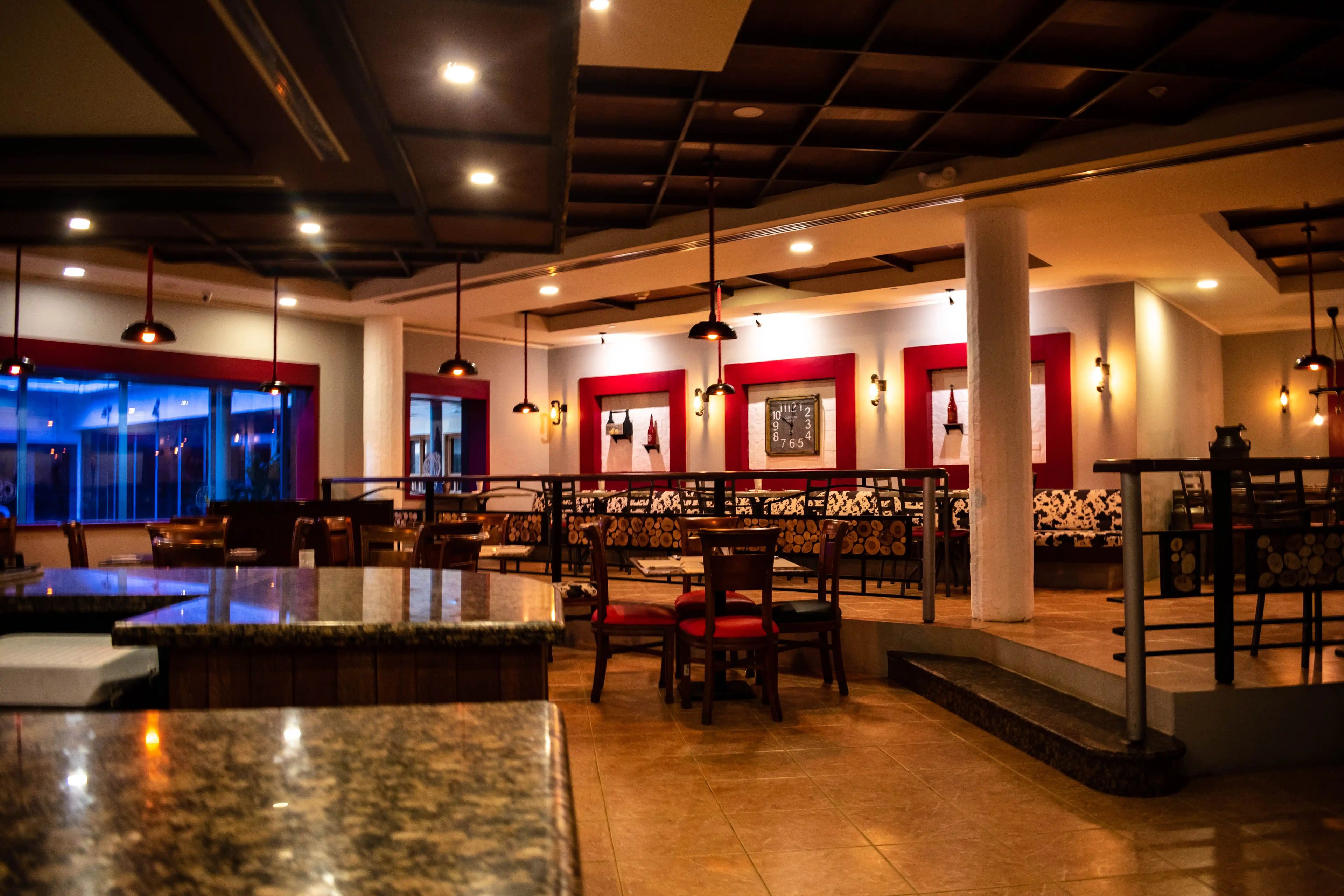 A restaurant interior with high ceilings, pendant lighting, and a mix of seating arrangements including tables and booths.