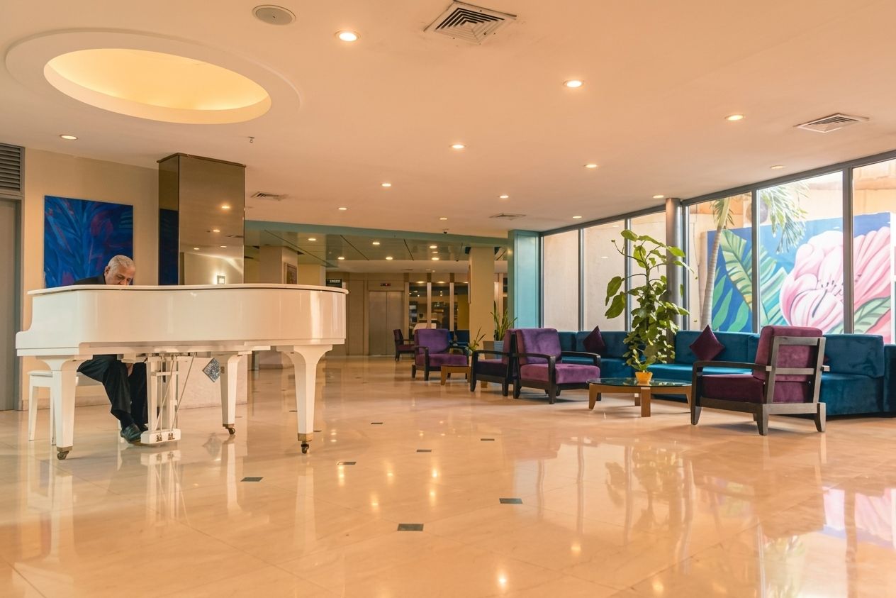 A spacious lobby with a grand piano, seating area with sofas, and large windows.