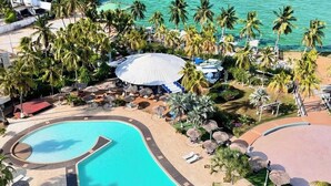 A resort with a large swimming pool, palm trees, and a beach area. - Hotel Tibisay Maracaibo (Maracaibo)
