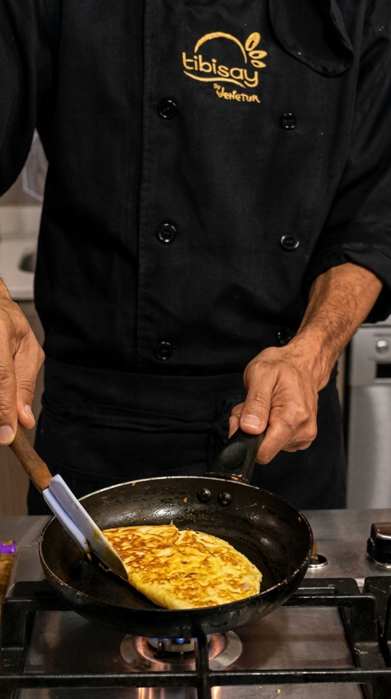 A person cooking an omelette in a pan on a stove.