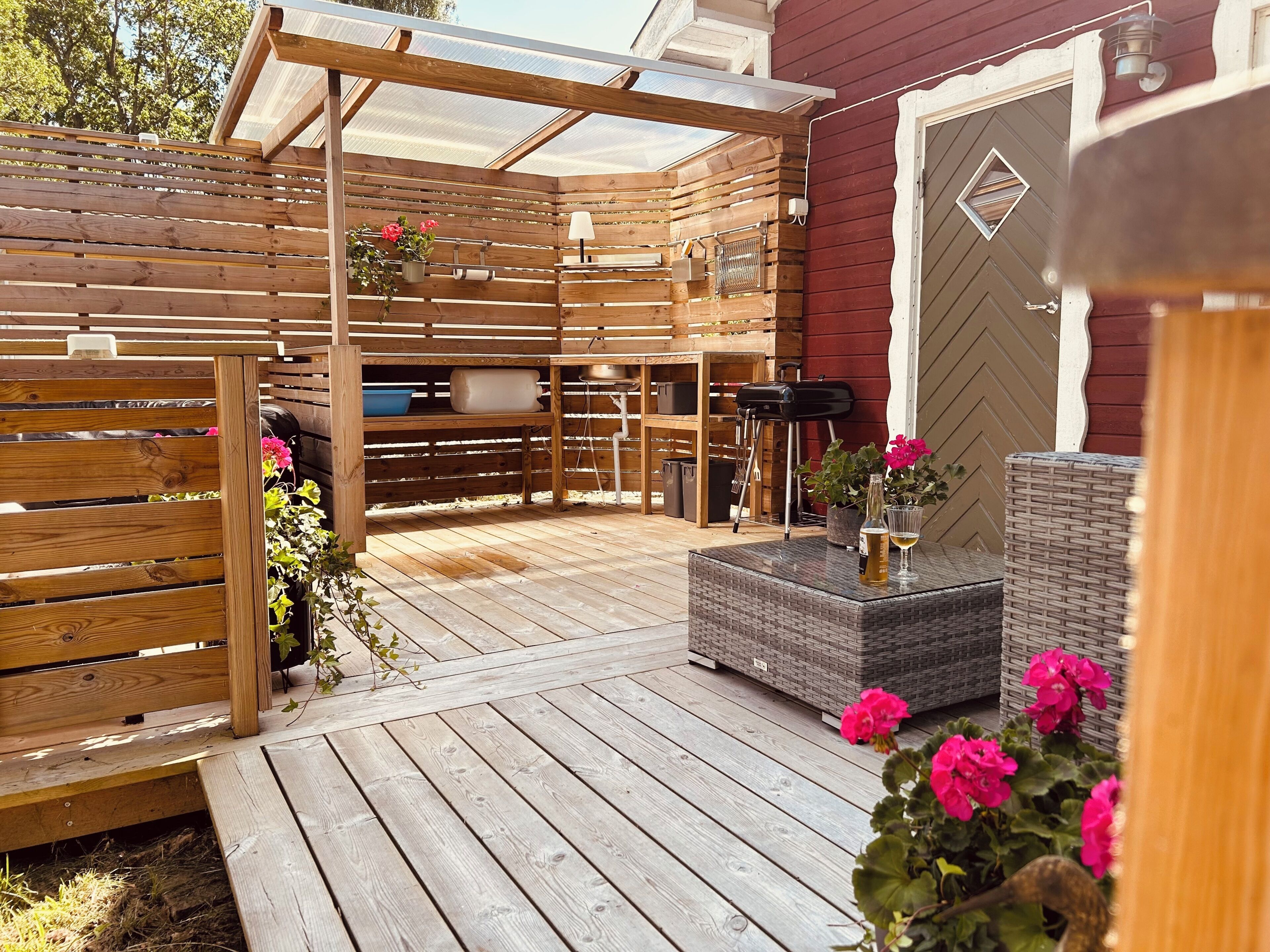 Une terrasse en bois avec une pergola, un espace salon extérieur et un coin barbecue.