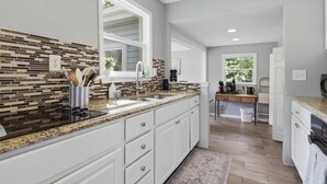 Uma cozinha moderna com bancada de granito, armários brancos e painel de azulejos coloridos.