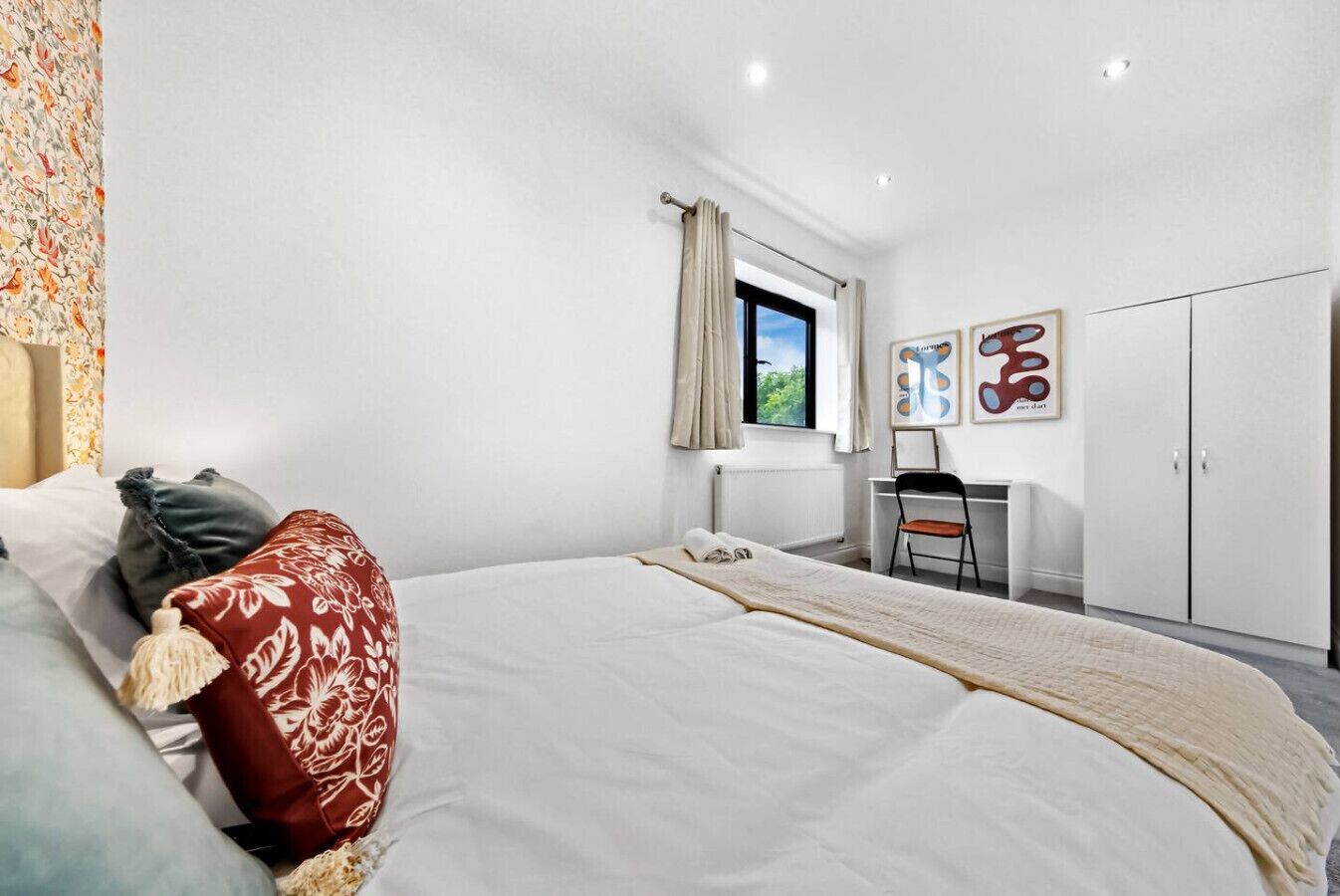 A bedroom with a bed, a desk, and a wardrobe.