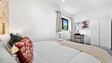 A bedroom with a bed, a desk, and a wardrobe.
