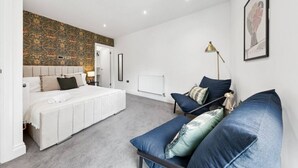 Quarto com cama, sofá, radiador, luminária e um quadro na parede.