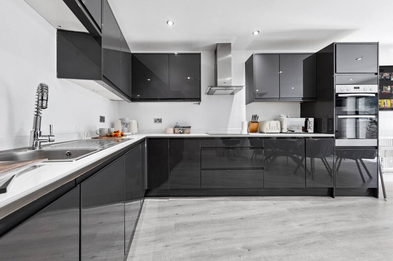 Une cuisine moderne avec des meubles de couleur sombre, des appareils en acier inoxydable et un design minimaliste.