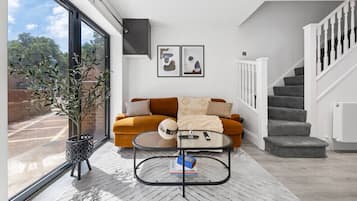A modern living room with a sofa, coffee table, and a staircase.