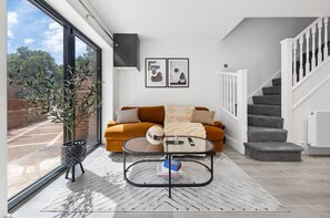 A modern living room with a sofa, coffee table, and a staircase.