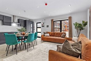 A modern apartment with a dining area, a living room with a sofa, and a kitchen. - Luxurious 5 BED | Sleeps 14 | Tower Bridge (Greater London)