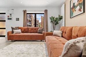 Ein modernes Wohnzimmer mit zwei Sofas, einem großen Fenster und einer Pflanze.
