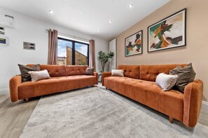 A modern living room with two sofas, a large window, and abstract art on the wall. - Luxurious 5 BED | Sleeps 14 | Tower Bridge (Greater London)