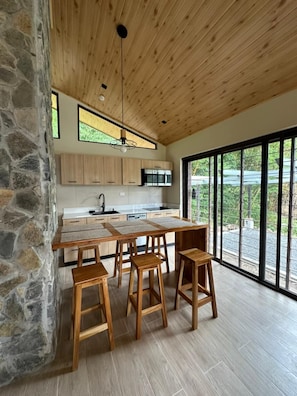 Eine moderne Küche mit Holzausstattung, einer großen Kochinsel und einem Essbereich mit Holzstühlen.