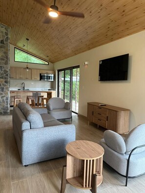Ein modernes Wohnzimmer mit einer Couch, Sesseln, einem Couchtisch und einem Fernseher.