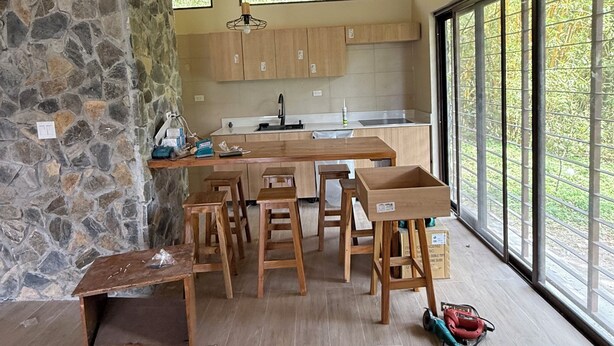 A modern kitchen with a stone wall, wooden ceiling, and large windows.