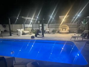 Ein Pool mit blauer Färbung, umgeben von Gartenmöbeln und Blumentöpfen.
