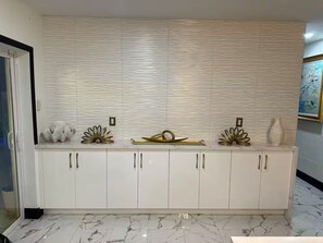 A kitchen with white cabinets, a marble floor, and decorative items on the countertop. - Cafe Estate (Hollywood)