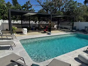 A swimming pool with lounge chairs and a covered seating area. - Cafe Estate (Hollywood)