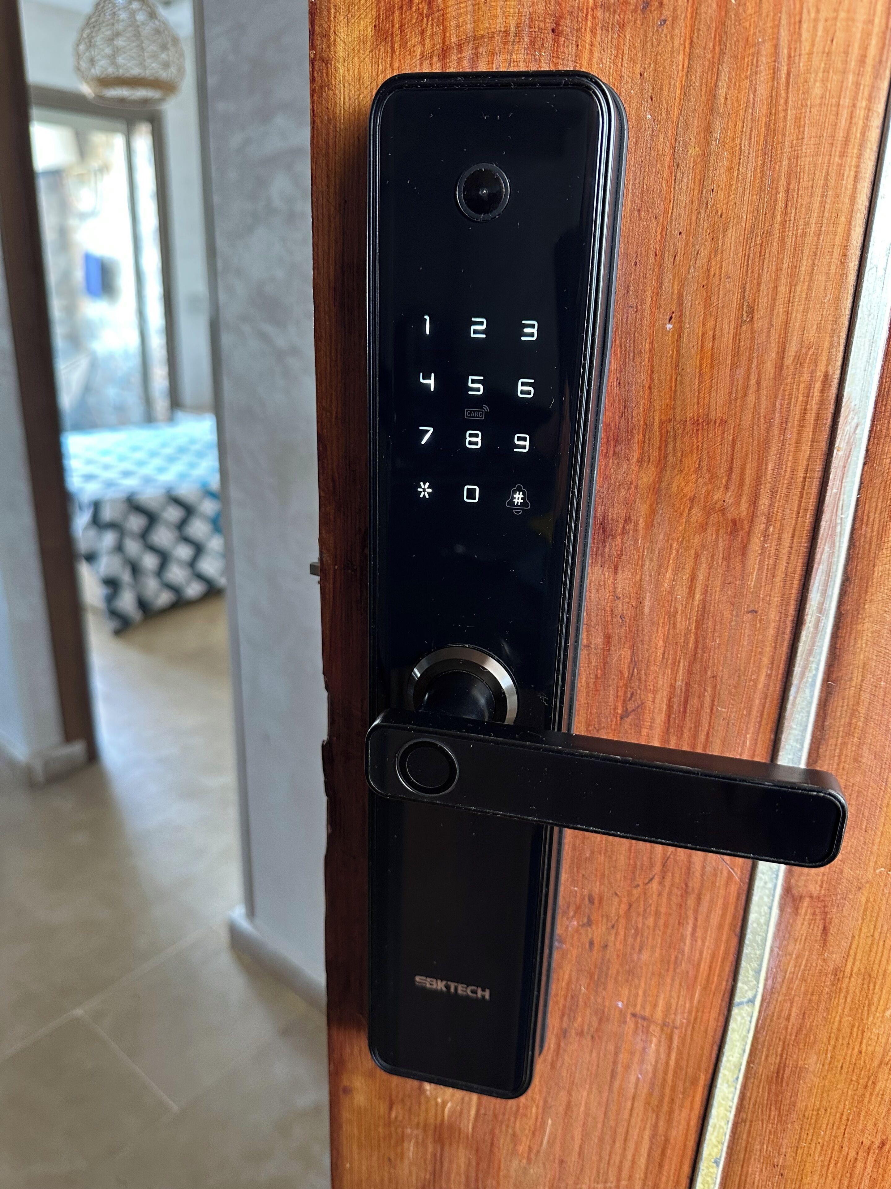 Une serrure à clavier électronique noire, montée sur une porte en bois.