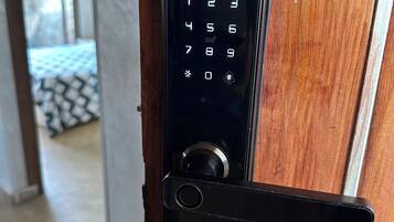 Une serrure à clavier électronique noire, montée sur une porte en bois.