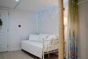 A white bed in a room with a ceiling light fixture and a wall-mounted light. - Peaceful 4-bedroom apartment with AC in vibrant Flushing (Flushing)