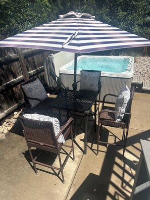 A patio area with a hot tub, wicker chairs, a table, and a striped umbrella. - Large 3+bdr, 2 bth, Boulder Retreat: Hot Tub, Flatiron Views & Close to downtown (Boulder)
