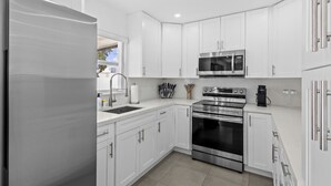 A modern kitchen with white cabinets, stainless steel appliances, and a built-in oven. - El    Paso (Miami)