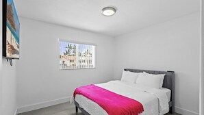 A bedroom with a bed, a window with a view, and a ceiling light. - El    Paso (Miami)