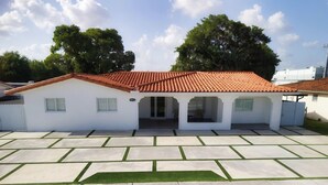 A single-story building with a red-tiled roof, a covered patio area, and a paved driveway. - El    Paso (Miami)