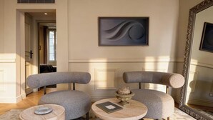 Una sala de estar moderna con dos sillones grises, una mesa de centro redonda de madera y una escultura decorativa de piedra.