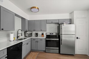 A modern kitchen with grey cabinets, a stainless steel refrigerator, a built-in oven, and a dishwasher. - 3-bedroom condo conveniently located near Campus and the Square! (Oxford)