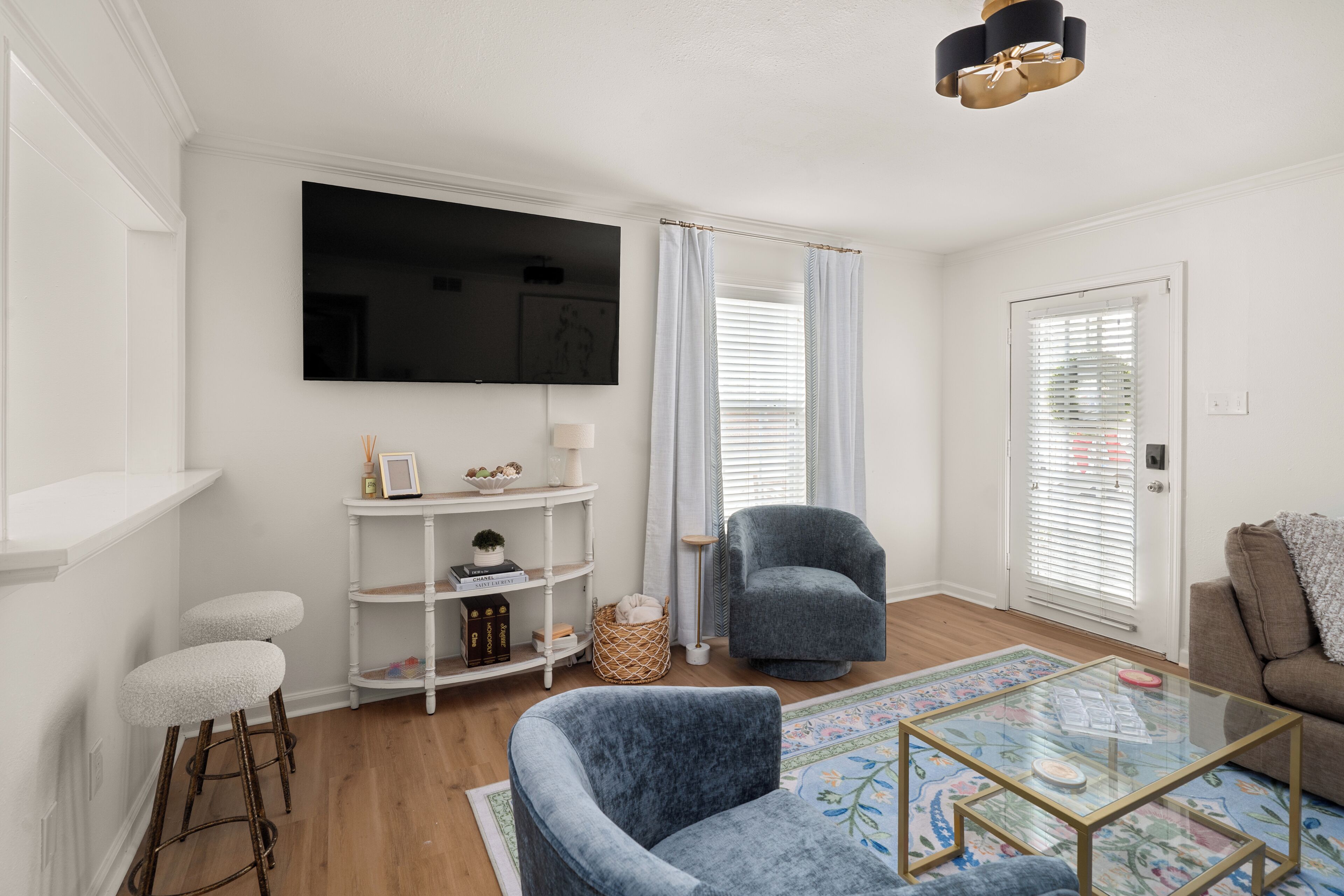 Ein modernes Wohnzimmer mit einem Flachbildfernseher, einem blauen Sessel, einem Glastisch und einem braunen Sofa.