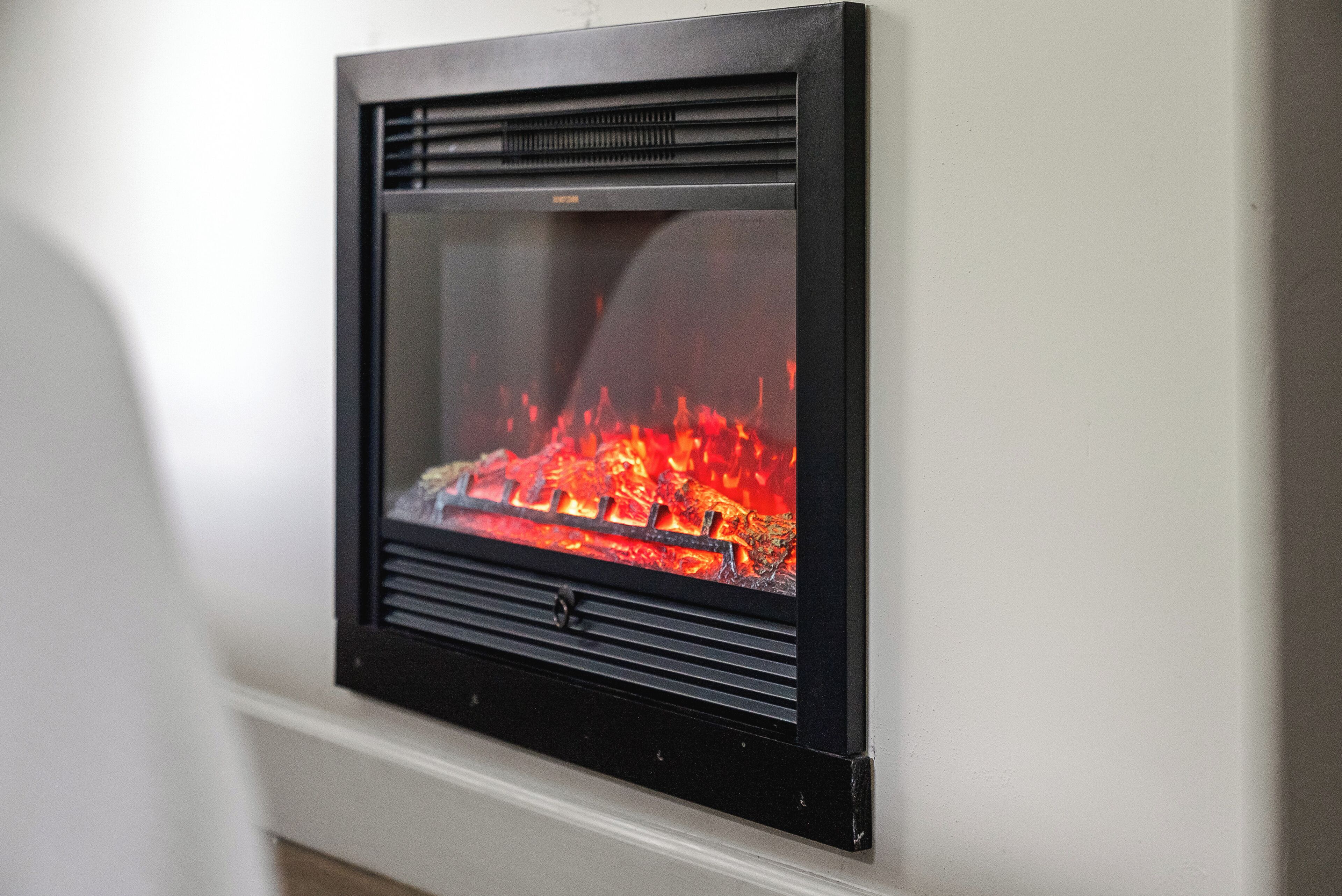 Ein an der Wand befestigter Kamin mit sichtbarem Feuer.