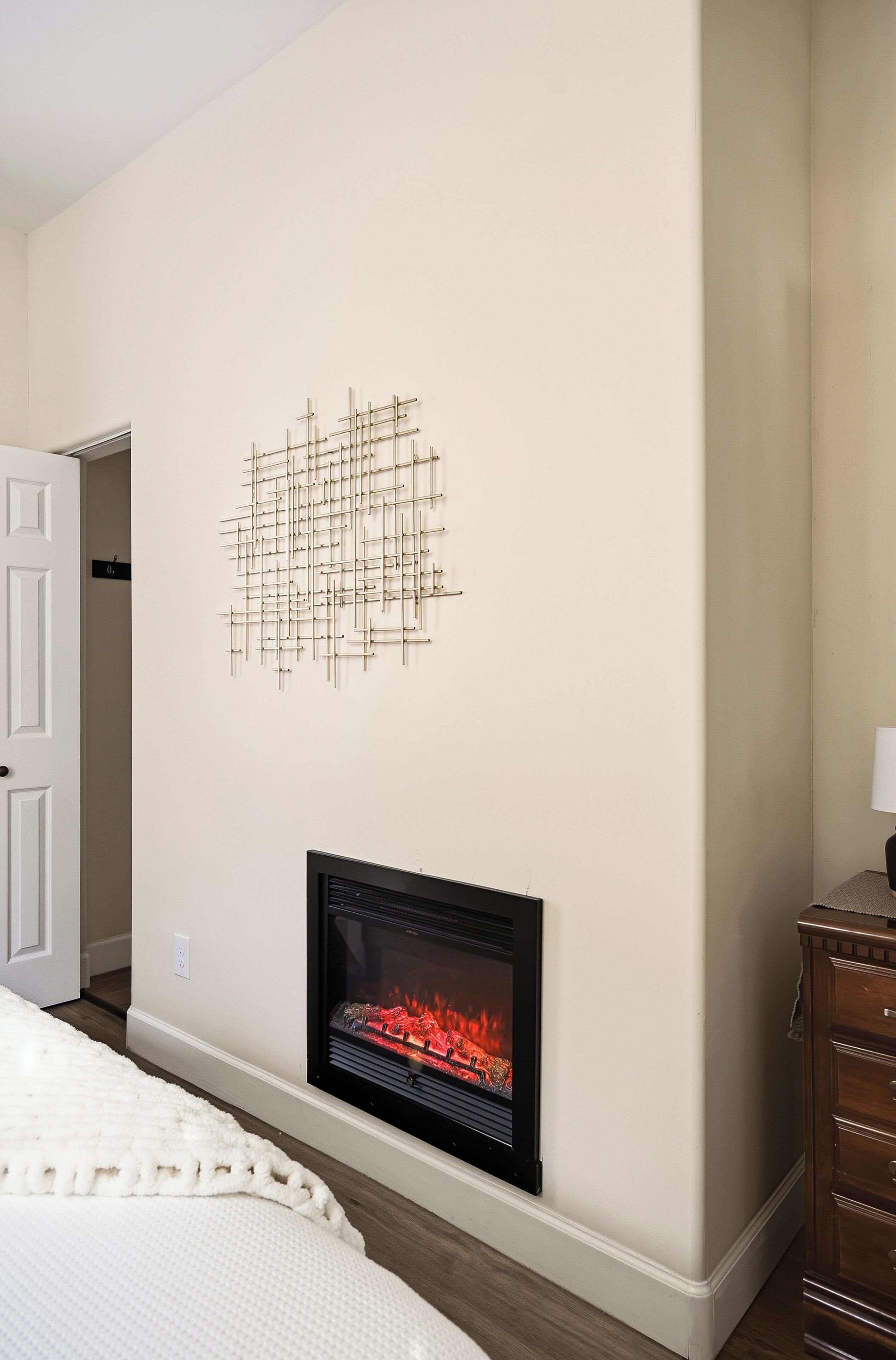 A room with a fireplace, a door, and a wall-mounted abstract art piece.