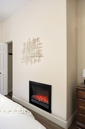 Una habitación con chimenea, una puerta y un cuadro abstracto colgado en la pared.