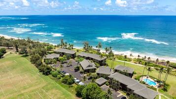 An aerial view of a resort with multiple buildings, a swimming pool, and a beach.