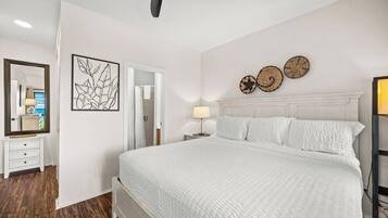 Ein Schlafzimmer mit Bett, Deckenventilator, Nachttisch, Spiegel und Wanddekoration.