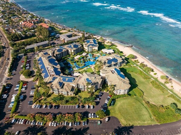 An aerial view of a resort with multiple buildings, a parking lot, and a beach. - Waipouli C102 / 2 King Beds / AC  / Pool (Kapaʻa)