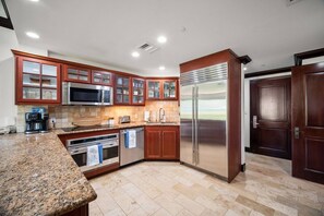 A modern kitchen with granite countertops, stainless steel appliances, and wooden cabinetry. - Waipouli C102 / 2 King Beds / AC  / Pool (Kapaʻa)