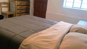 A bedroom with a bed, a dresser, a television, and a window.