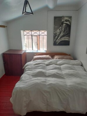 Un dormitorio con cama, ventana, cuadro y armario.