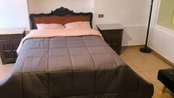 Ein Schlafzimmer mit einem Bett, einem Nachttisch, einer Stehlampe und einem Regal mit einer Topfpflanze.