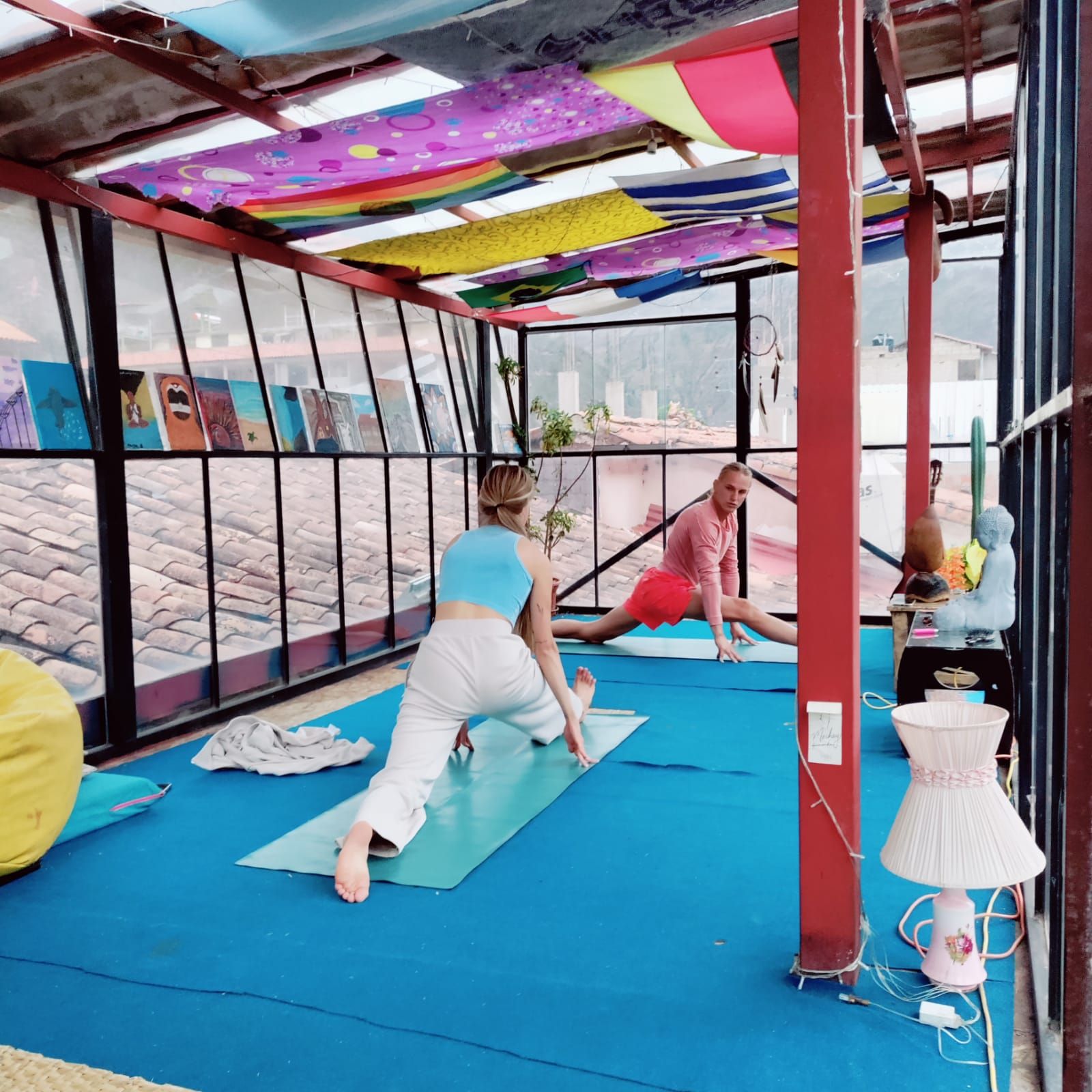 Un studio de yoga doté d’un mur en verre, de tapis de sol et d’un plafond décoré de tissus colorés.