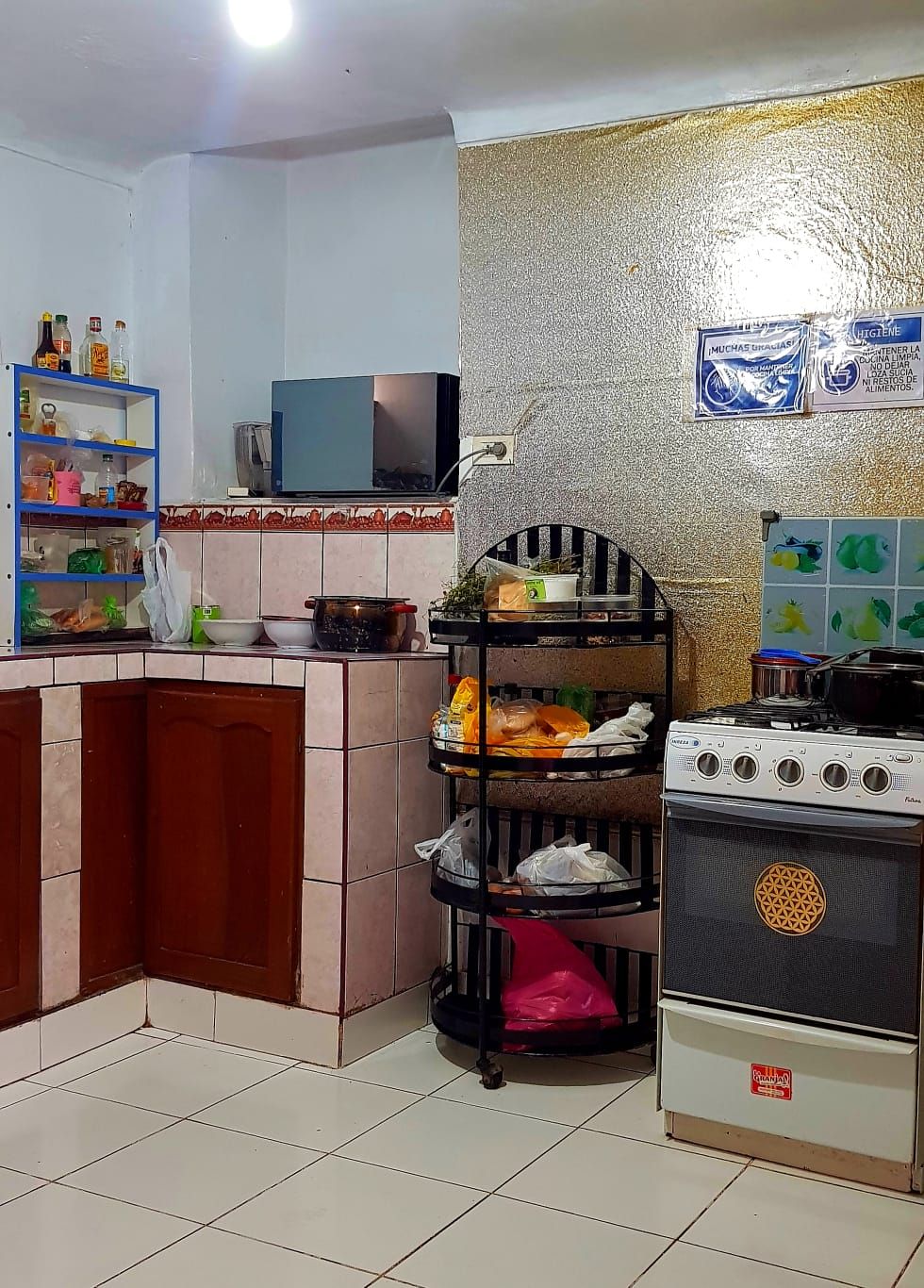 A kitchen with a stove, shelves, and a tiled floor.