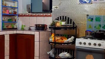 A kitchen with a stove, shelves, and a tiled floor.