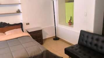 Een slaapkamer met een bed, een zwarte bank, een vloerlamp en een raam met uitzicht.