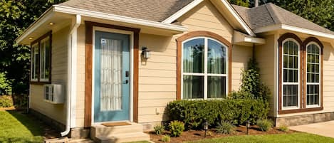 A single-story house with a front porch, a blue door, and a small front yard.