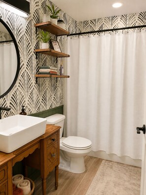 A bathroom with a white sink, wooden vanity, a toilet, and a shower curtain. - OKC 1 Bed 1 Bath Mini Guesthouse - The Margot (Oklahoma City)